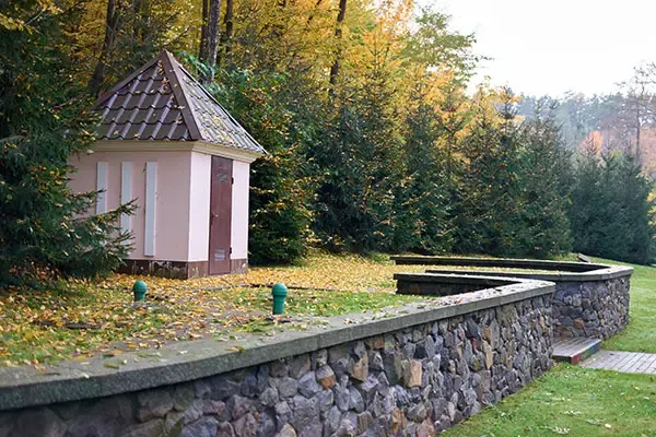 Old stone garden wall beside a lawn and a small garden building