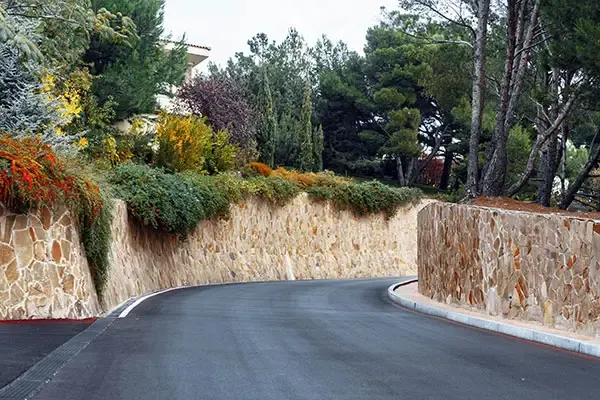 Tall stone-faced retaining walls along a winding sloping road